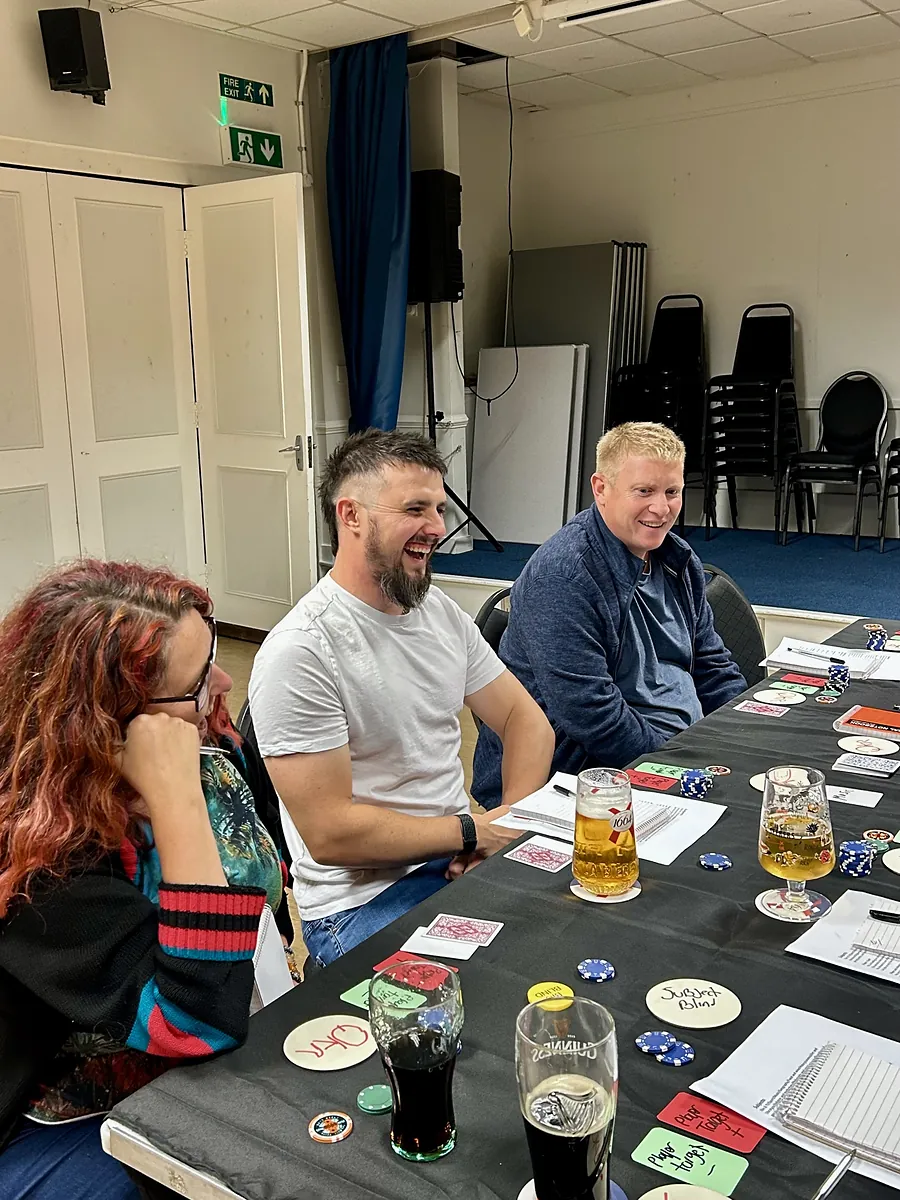 Two players grinning across the table mid-hand, chips and cards in front of them.